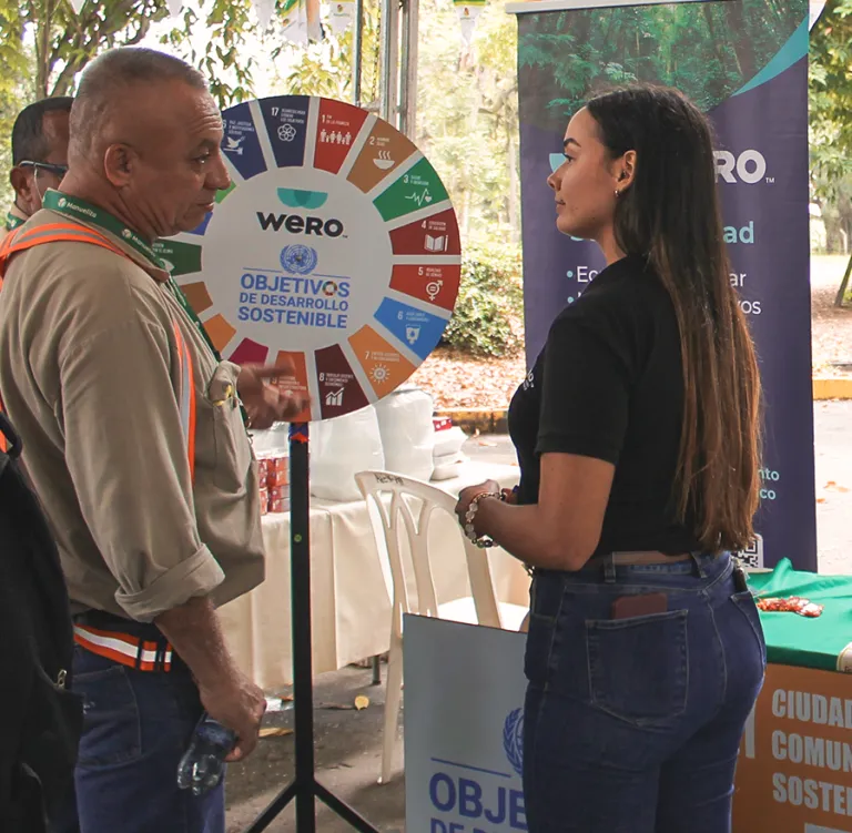 Conversación frente a una ruleta de los Objetivos de Desarrollo Sostenible en un evento de Wero